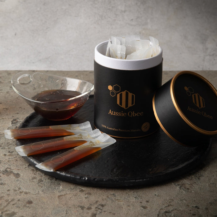 Manuka Honey MGO 150+ 360g packaging with single-serve sachets and honey in a bowl on a stone surface.