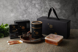 Collection of black and gold products on a textured surface with a gray background